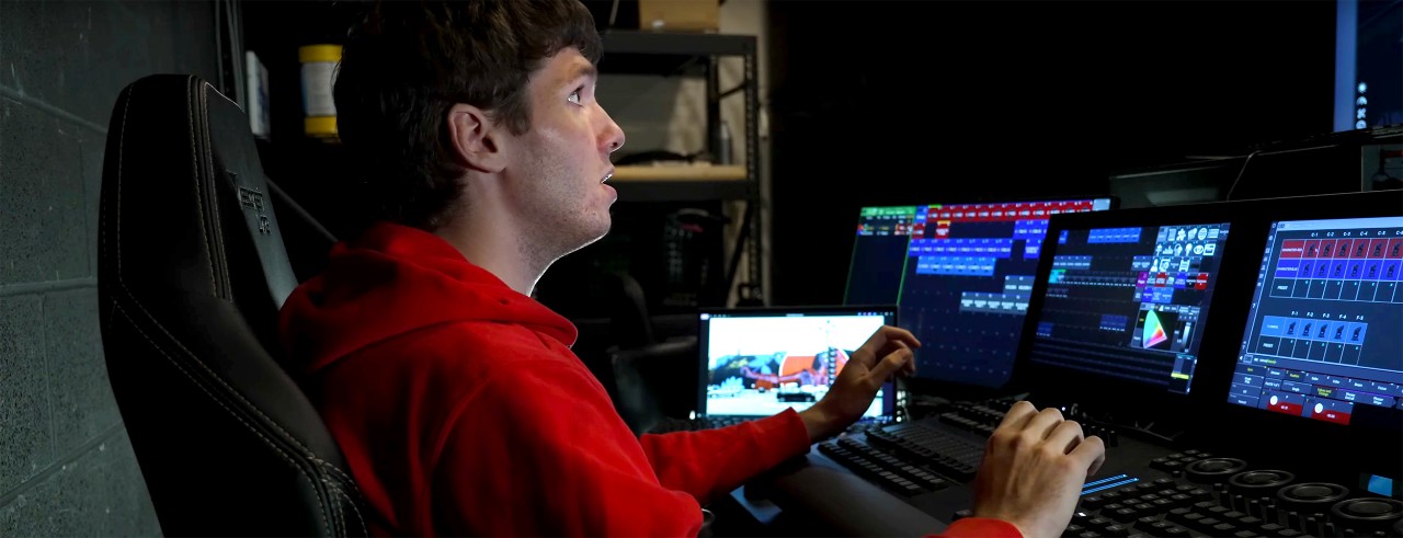 Lighting Design and Technology MFA student Lucas Inman sits at a control console in CCM's Light Lab & Classroom Training Center in a scene from the "Blink: A Spotlight on CCM" mini documentary.