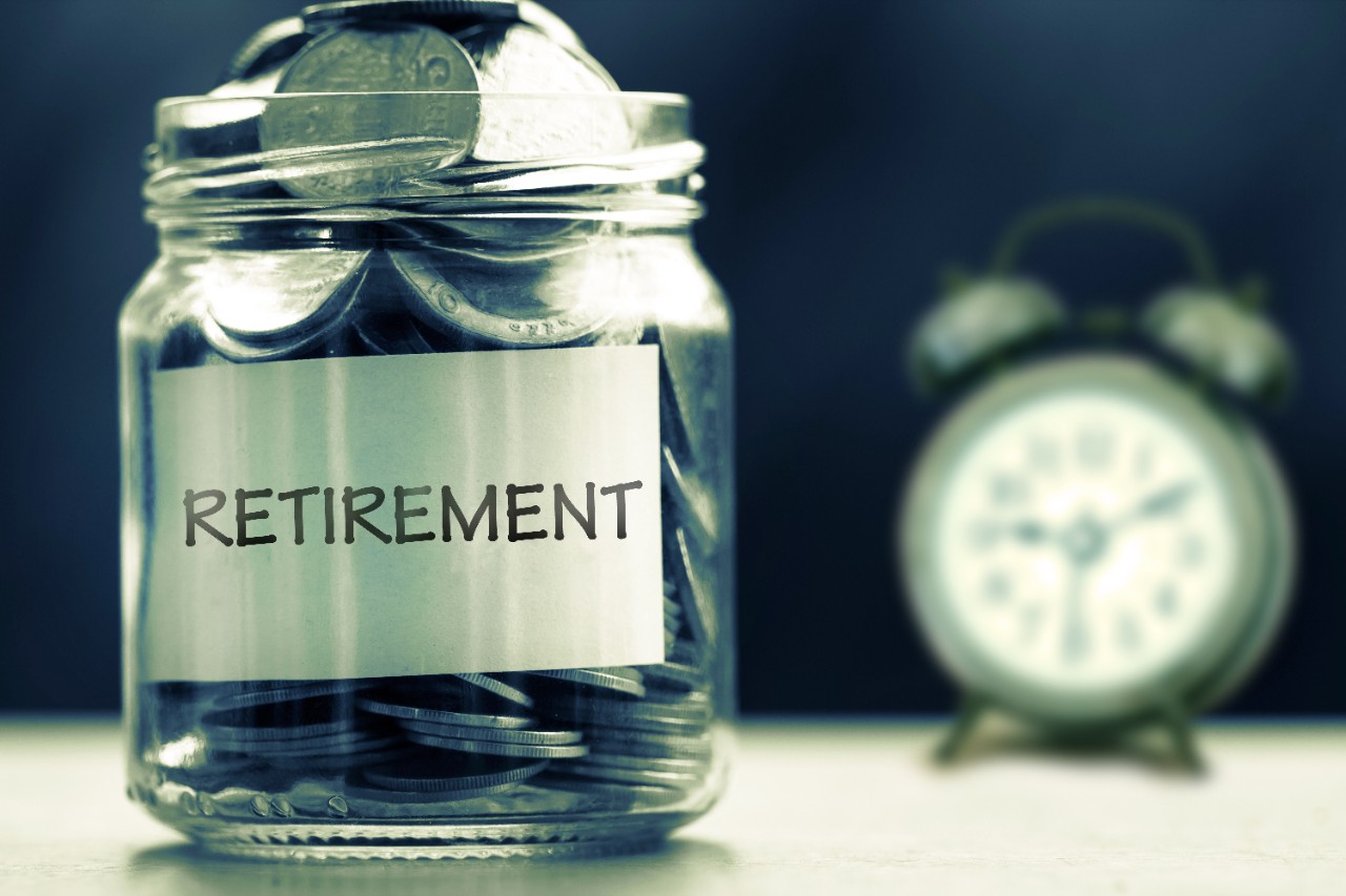 A jar of coins labeled "retirement" with a clock in the background
