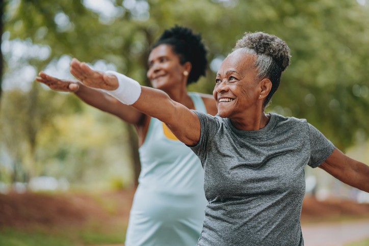 Two women do yoga outside