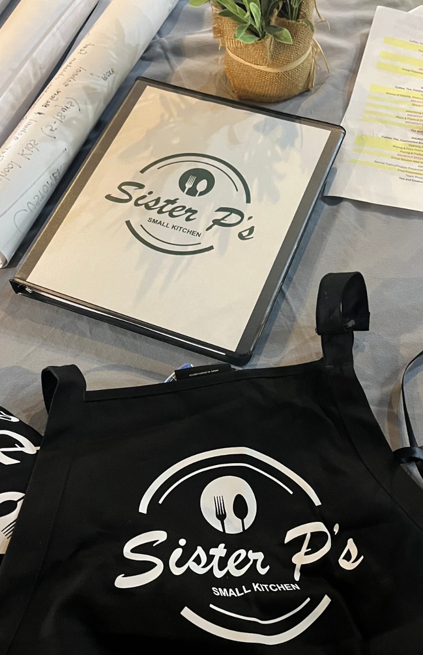 A binder and apron with Sister P's new logo