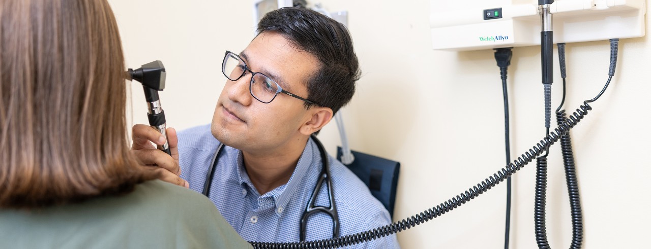 A medical student uses a otoscope to look into the ear of another medical student 