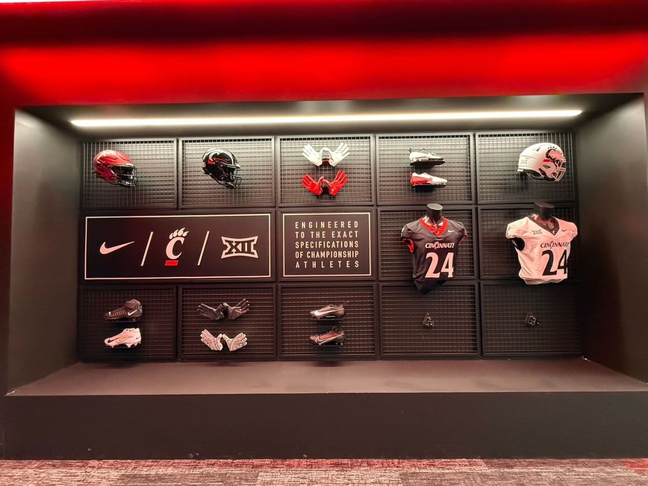 A display of Bearcats football shoulder pads, helmets, gloves and cleats in the new Sheakley Indoor Practice Facility and Athletics Performance Center
