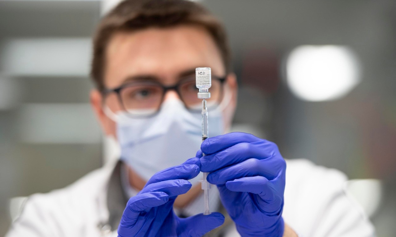 Public health professional in PPE holding syringe