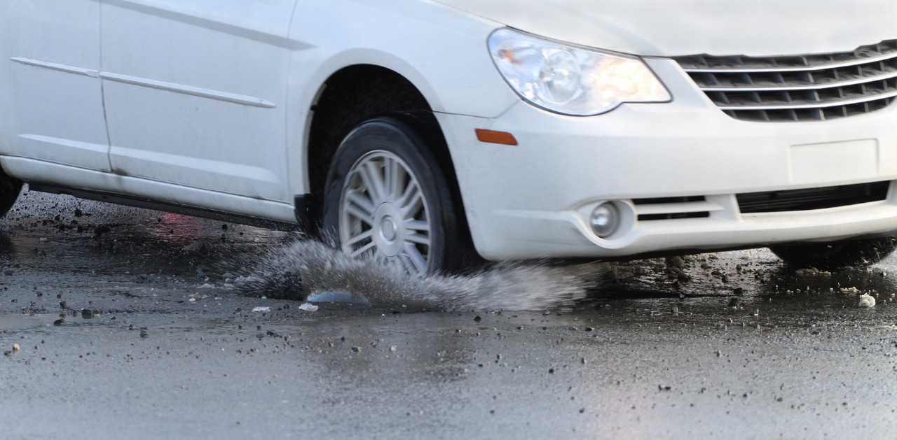 A car runs over a pothole.