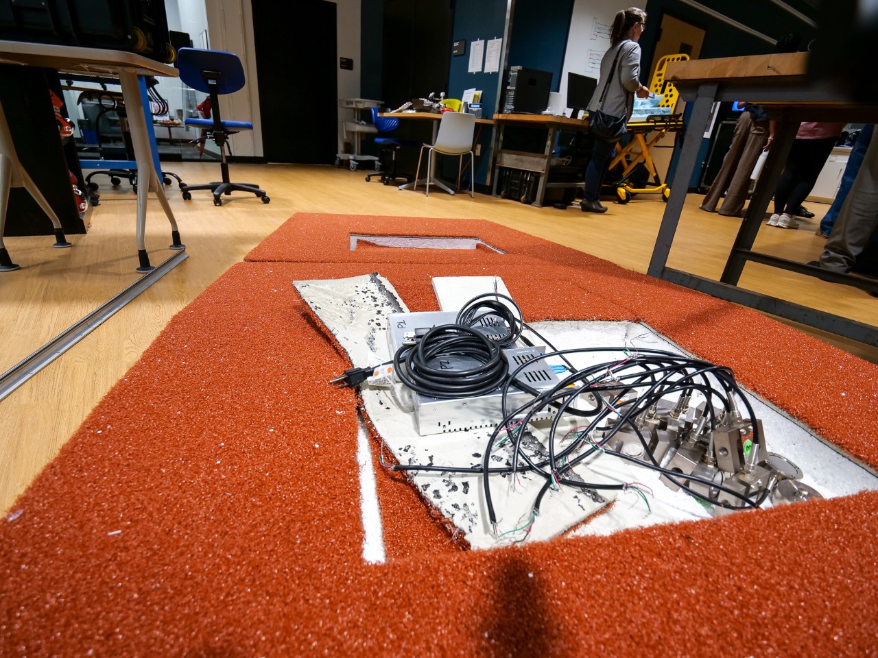 An artificial pitcher's mound has a sunken well full of wires and cables. 