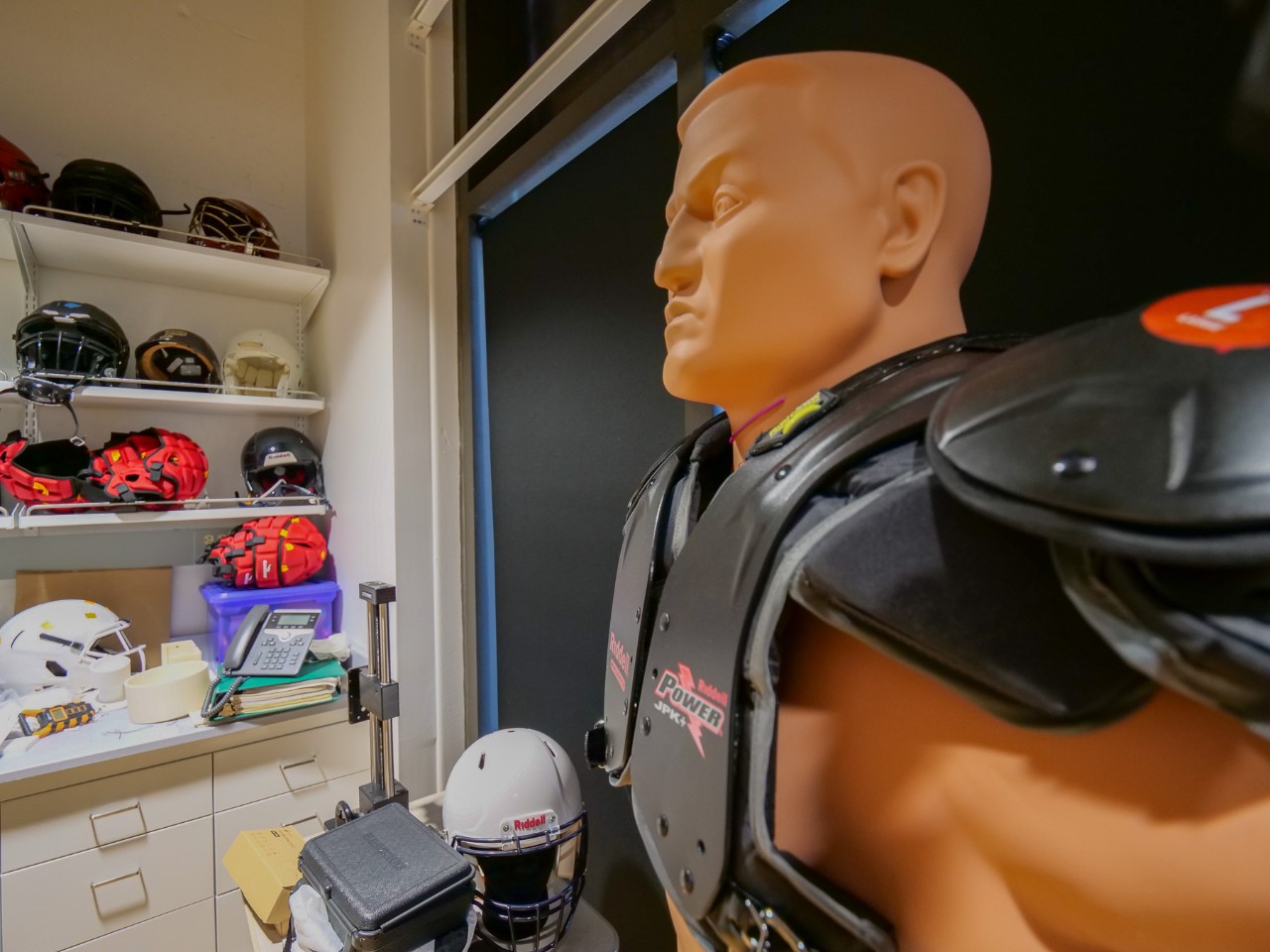 A mannequin in football pads in a lab.