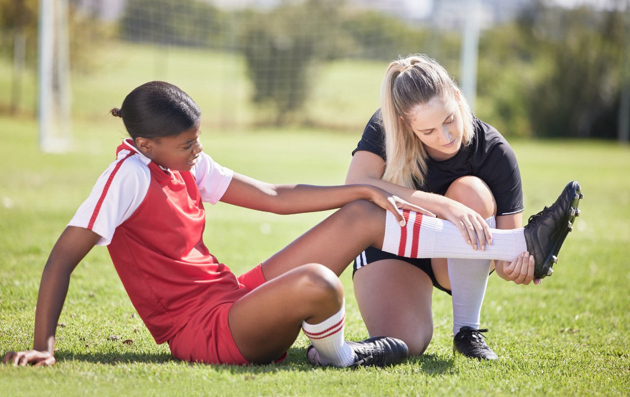An athletic trainer tends to a soccer player's ankle