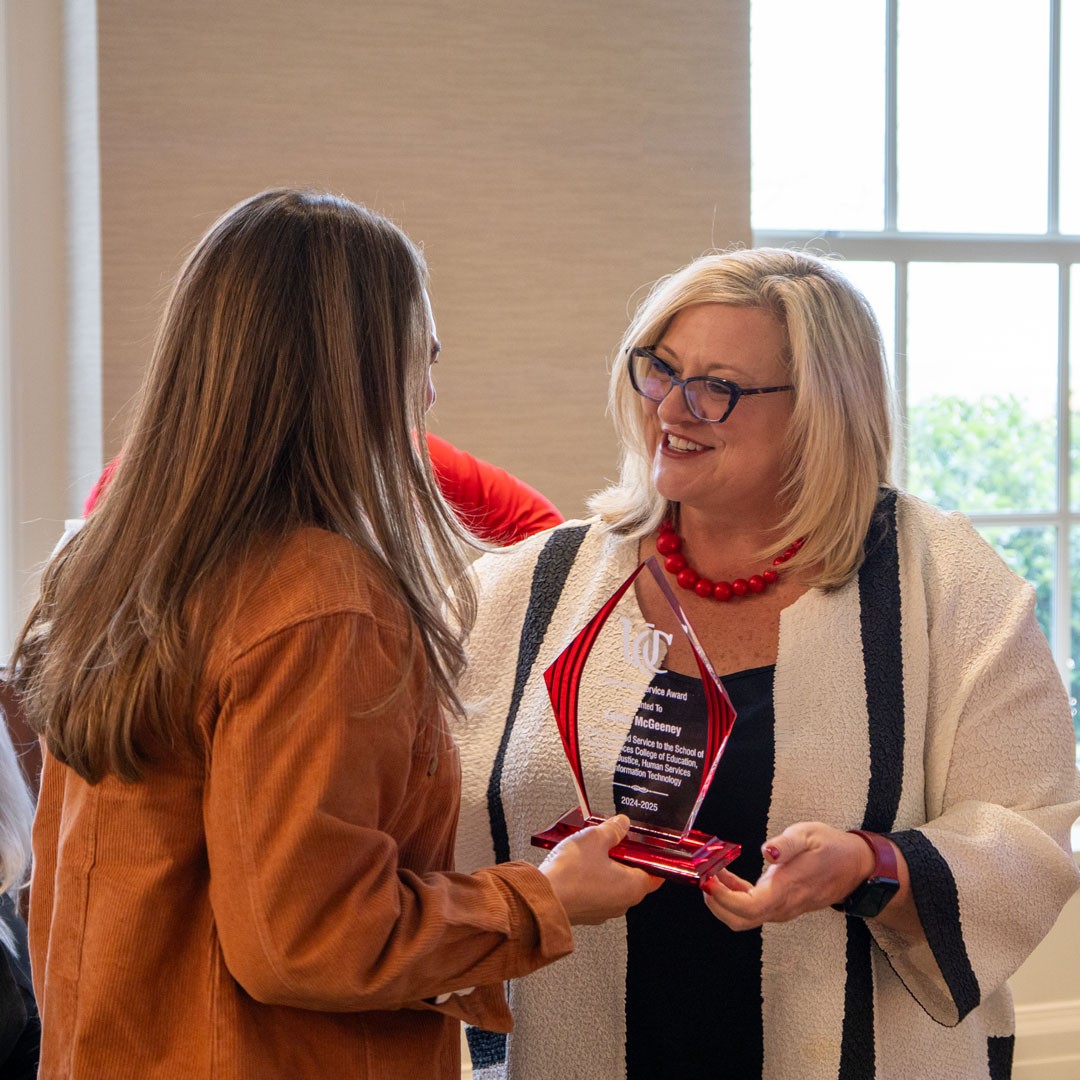Dean Huffman hands a clear glass award to a CECH community member