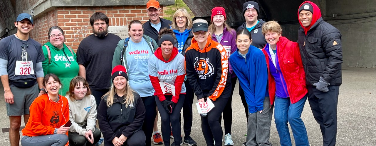 Members of the 2023 Walk Ahead for Brain Tumor Discoveries Shepherd Color team stand together in front of a Sawyer Point brick pillar.