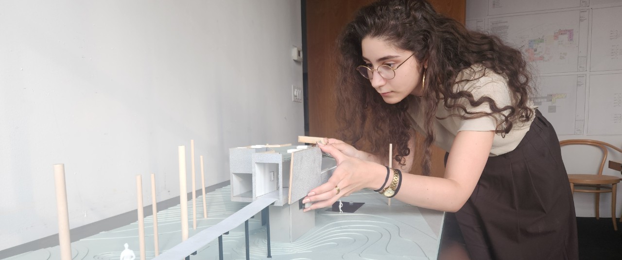 Architecture graduate student Tamara Nasr working with a design model on a large table