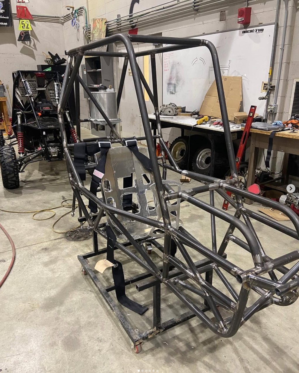 A metal all-terrain vehicle frame sits on the floor of a garage.