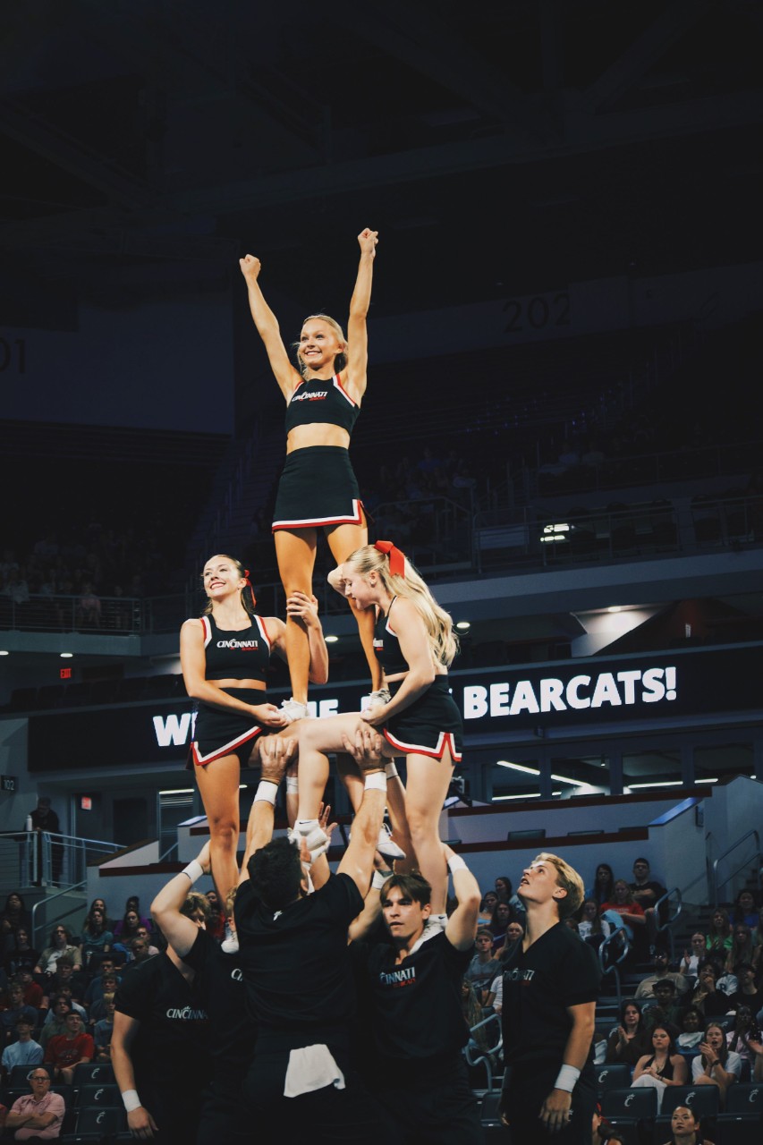 A dozen students with four female cheerleaders on top form a pyramid in fifth third arena