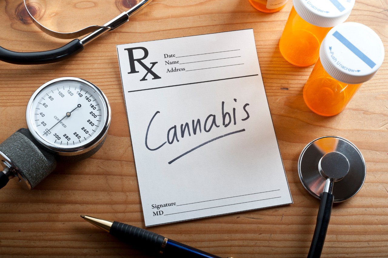 prescription bottles with a note pad saying cannabis along with a stethoscope nearby