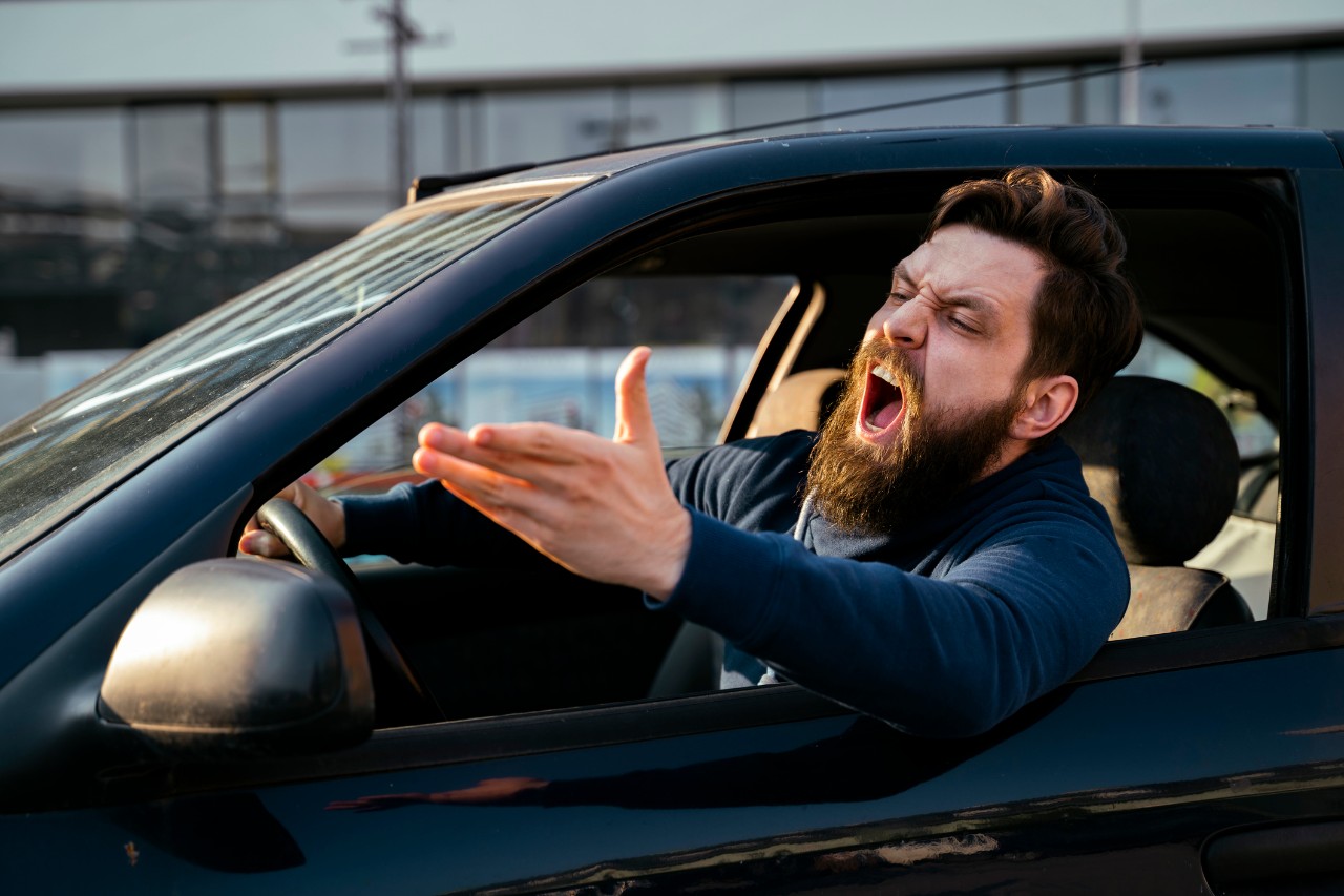A driver gestures angrily out his window.