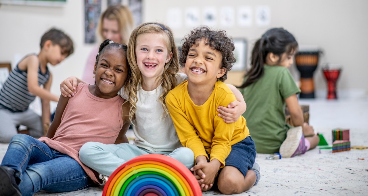 children sitting on the floor with a rainbow in front of them