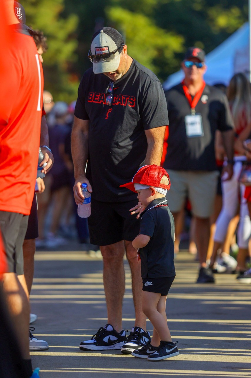 grandfather wearing UC T-shirt with young grandkid at a tailgate