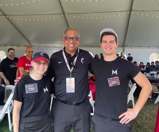 Noelle Scheper and Jaden Walton stand with UC President Pinto.