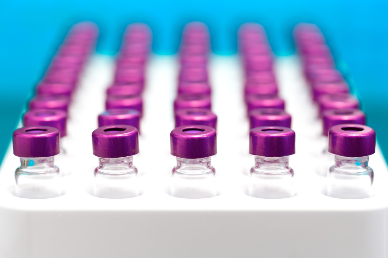 Rows of vials with purple lids in a tray 