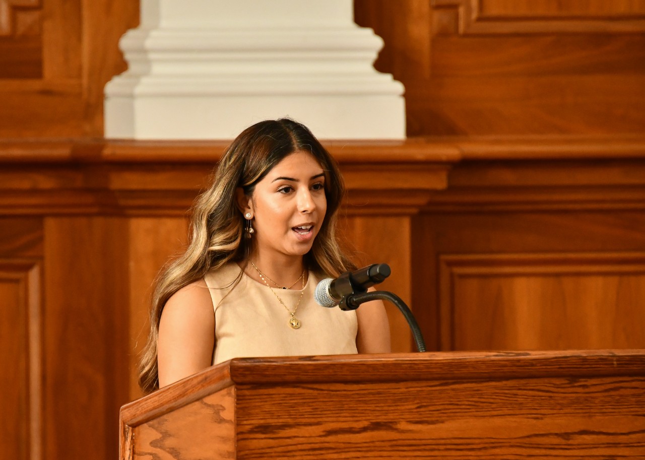 Selma Younes stands at a podium in Probasco Auditorium.
