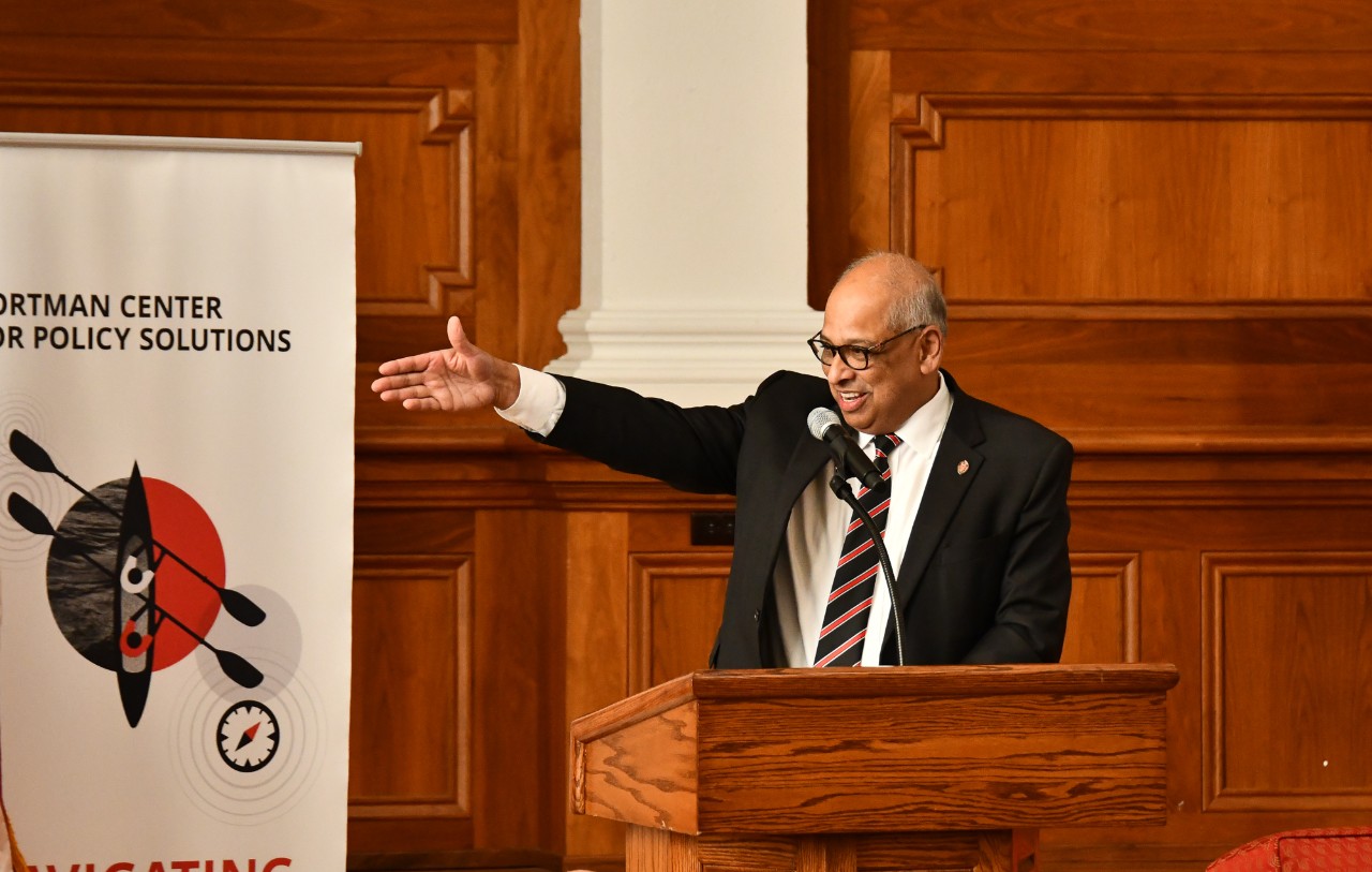 Neville Pinto gestures while talking at a podium.