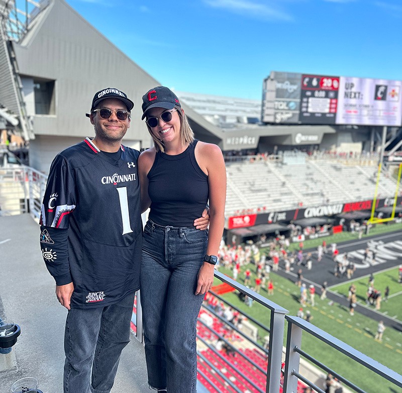 Sarah Mullins and partner pose in Nippert Stadium during a Cincinnati Bearcats football game