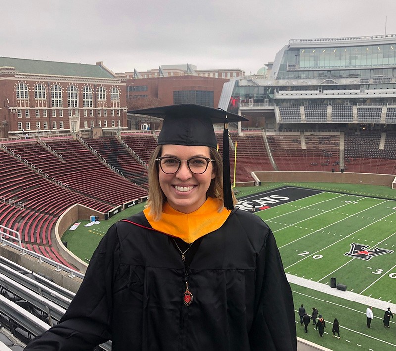Sarah Mullins poses in a grad cap in Nippert Stadium