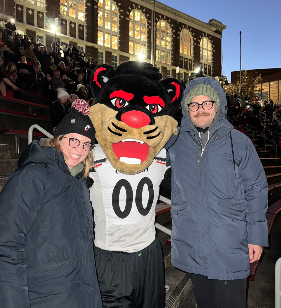Sarah Mullins and partner pose with the Bearcat in Nippert Stadium during a Cincinnati Bearcats football game