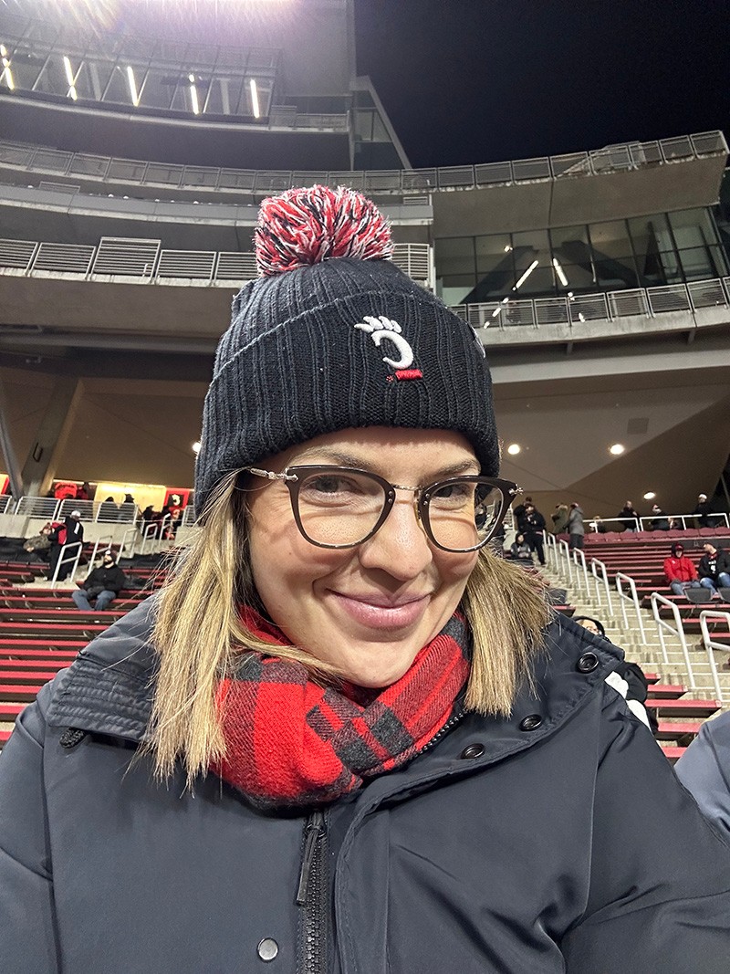 Sarah Mullins poses in Nippert Stadium wearing a UC Bearcats winter hat